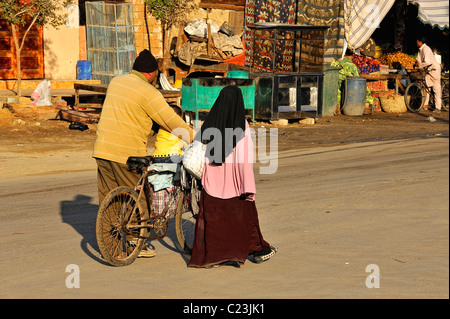 Ägyptischen paar mit einer Frau verschleiert, typische Kleidung zu tragen und zu Fuß in einer Straße in der Stadt von Siwa, westliche Wüste, Ägypten Stockfoto