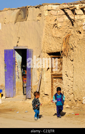 Zwei Jungen spielen auf einer schmutzigen Straße vor einem Haus in der Stadt Siwa, westliche Wüste, Ägypten Stockfoto