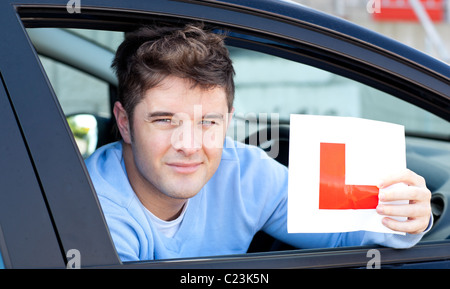 Positvie junge männliche Fahrer mit einem L-Schild Stockfoto