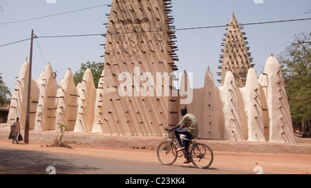 Ein Radfahrer geht die Grande Mosquée in Bobo Dioulasso Stockfoto