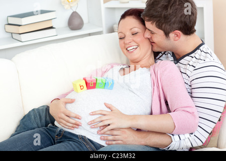 Porträt einer glücklichen schwangeren Frau mit Baby auf dem Bauch und ihres Mannes, küsste sie auf eine Stockfoto