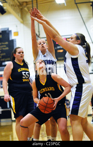 Ein High School Spieler hat mit der Verteidigung zu beschäftigen, während sie versuchen, einen Kurs für die Hoop von rechts nach Grundstück unter dem Korb. USA. Stockfoto