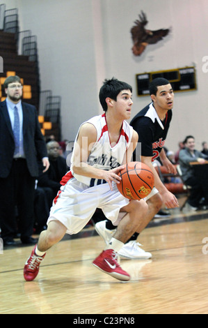 Point Guard Laufwerke hinter einem Verteidiger einrichten eine Bewertung durch ein mannschaftskamerad in einer High School Basketball nachsaison Endspiel Spiel. USA. Stockfoto