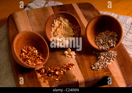 Drei Gewürze, roter Pfeffer, getrockneten Senf und Fenchelsamen, spill auf eine dreifarbige Schneidebrett. Stockfoto