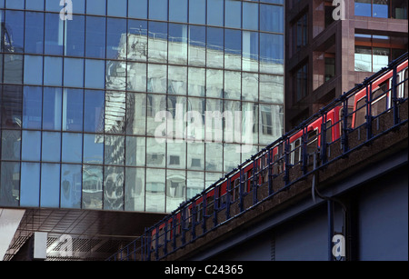 Eingabe von Heron Quays Station Canary Wharf, London mit Reflexionen an der Fassade des Gebäudes oberhalb der Station einen DLR-Zug Stockfoto