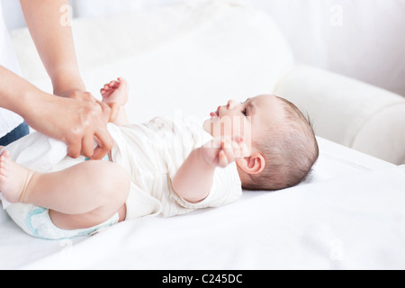 Nahaufnahme einer jungen Mutter die Windel ihres Babys auf einer Couch ändern Stockfoto