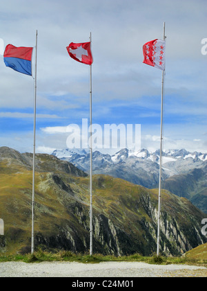 Fahnen der Schweiz (Mitte), Kanton Tessin (links) und Wallis (rechts) auf dem Nufenen Pass, Wallis / Tessin, Schweiz. Stockfoto