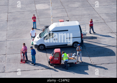 Die griechischen Arbeiter und Reisende warten auf die Ankunft der Fähre in den Hafen von Parikia auf der griechischen Kykladen-Insel Paros. Stockfoto