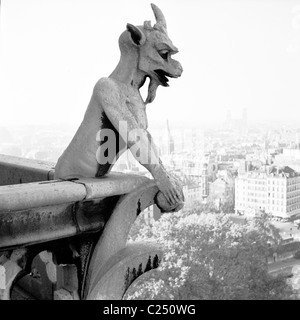 1950s, eine Chimäre auf der Kathedrale Notre-Dame über der Stadt Paris, Frankreich. Diese Chimäre sind eigentlich keine Gargoyles, sondern als Grotesken bekannt. Stockfoto