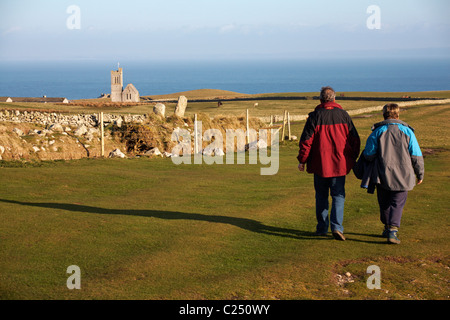 Paar Richtung St. Helena Kirche im Abendlicht auf Lundy Island, Devon, England UK im März - St Helens Kirche Stockfoto