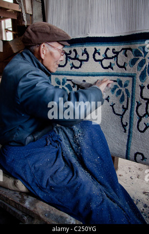 Eine ältere resident trimmen und finishing Teppiche an den tibetischen Flüchtlingen Selbsthilfe Zentrum in Darjeeling, Westbengalen, Indien. Stockfoto