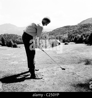 Deutschland der 1950er Jahre.  Männlichen Golfer am Abschlag mit Holzknüppel Adressierung den Ball auf dem Golfplatz in Baden-Baden. Stockfoto