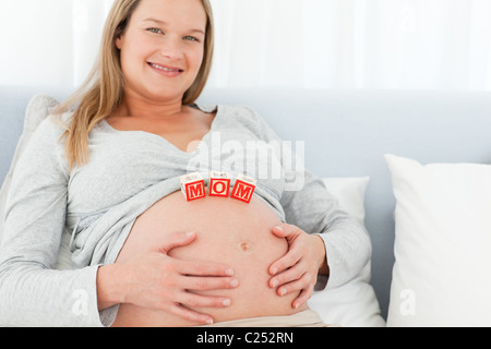 Blonde schwangere Frau mit Mutter Briefe auf dem Bauch liegend auf einem Bett Stockfoto