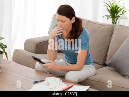 Ängstliche Frau ihre Schulden sitzen im Wohnzimmer-Berechnung Stockfoto