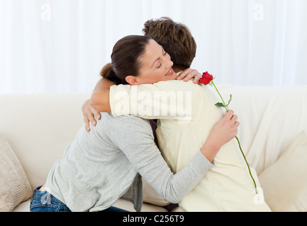 Schöne Frau umarmt seinen Freund nach Erhalt einer Blume Stockfoto