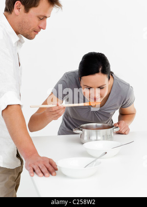 Nette Frau, die Verkostung ihrer Suppe mit ihrem Mann in der Küche Stockfoto