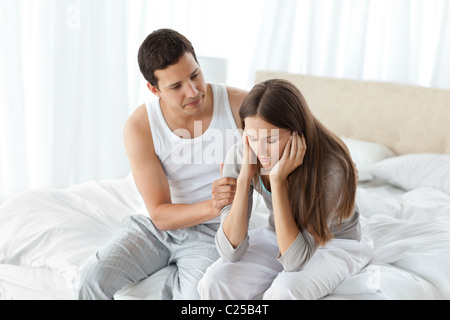 Gut aussehender Mann tröstete seine Freundin zusammen auf dem Bett Stockfoto