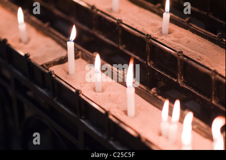 Brennende Kerzen, setzte sich in einen gefüllten Sandkasten in einer Kirche Stockfoto