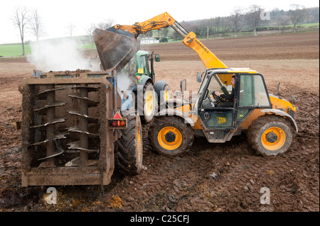 Muckspreader mit einem JCB Loadall be- Stockfoto