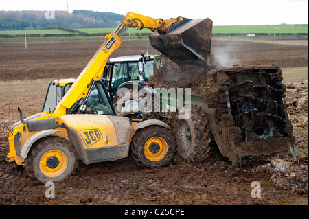 Muckspreader mit einem JCB Loadall be- Stockfoto