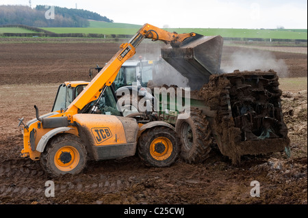 Muckspreader mit einem JCB Loadall be- Stockfoto