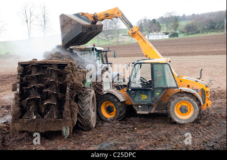 Muckspreader mit einem JCB Loadall be- Stockfoto