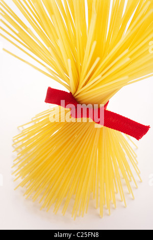 Reihe von Spaghetti gefesselt mit rotem Band isoliert auf weiss Stockfoto