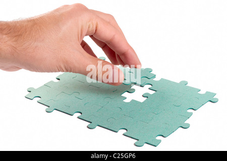 Hand, die fehlendes Stück Grün Puzzles in das Loch einsetzen Stockfoto