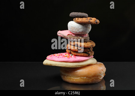 Haufen von Kekse und Süßigkeiten im Zen-Stack auf schwarzem Hintergrund Stockfoto