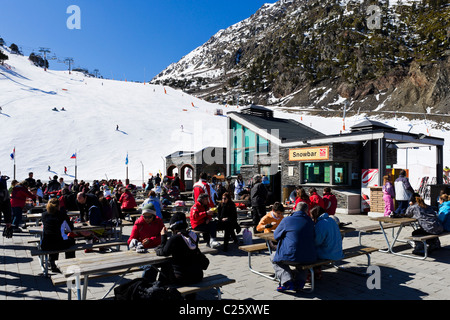 Skifahrer auf der Terrasse des Bergrestaurant am Comallempla mit den Skipisten hinter Arinsal, Skigebiet Vallnord, Andorra Stockfoto