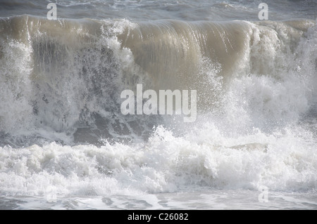 Ein stürmischer Tag am Meer. Eine große graue Kurve stürzt auf den Strand bei Burton Bradstock in Dorset. England, Vereinigtes Königreich. Stockfoto