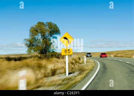 Bewegungsunschärfe Effekt - Links Kurve, 85 km/h Geschwindigkeit beratenden Zeichen. Rote und silberne Autos nähern. Stockfoto