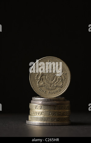 Ein Stapel von britischen Münzen mit einem Pfund-Münze auf der Kante stehen. Stockfoto