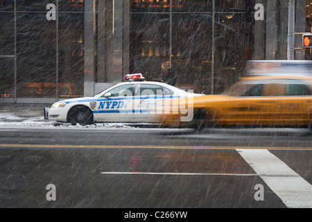 Taxi und Polizei Auto in New York Schnee. Motion blur Taxi. Times Square, NEW YORK CITY. Stationäre Polizeiauto durch schnelle Taxi überholt. Stockfoto