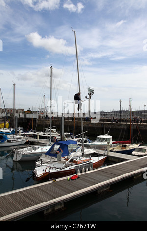 Mann, die Reparatur der Takelage auf den Mast einer Yacht im Hafen von Plymouth England Großbritannien Barbican Stockfoto