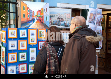 Menschen betrachten von Bildern für den Verkauf auf einen Künstler auf der Straße stand, Burano Dorf, Venedig, Italien Stockfoto