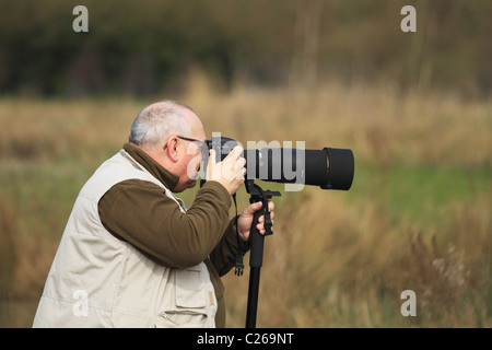 Ein Vogelbeobachter Fotografieren von Wildtieren durch ein Teleobjektiv an einem Vogelschutzgebiet in Arundel, East Sussex, England. Stockfoto