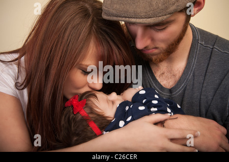 eine junge Mutter küssen ihr Babymädchen Stockfoto