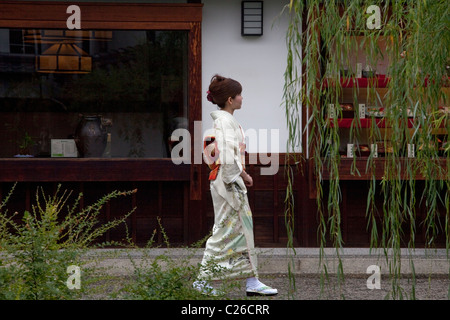 Frau im Kimono zu Fuß vor der Geschäfte im historischen Bezirk Bikan, Kurashiki, Japan. Stockfoto