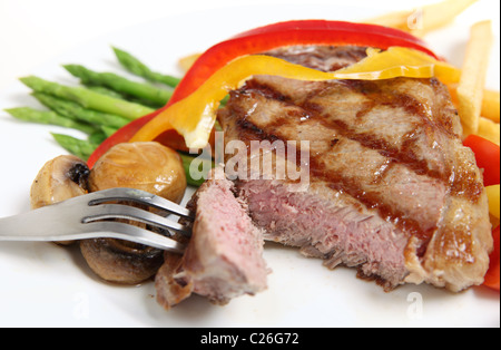 Ein perfekt zubereitetes Kalbfleisch Sirloin-Steak geschnitten geöffnet und serviert mit Champignons, Paprika-Bänder, Spargel, Pommes Frites. Stockfoto