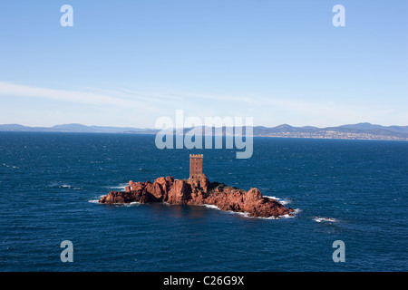 Kleine Insel mit atemberaubendem rotem vulkanischem Gestein, gekrönt von einem quadratischen Turm der gleichen Farbe. L'Île d'Or, Esterel Massif, Saint-Raphaël, Var, Frankreich. Stockfoto