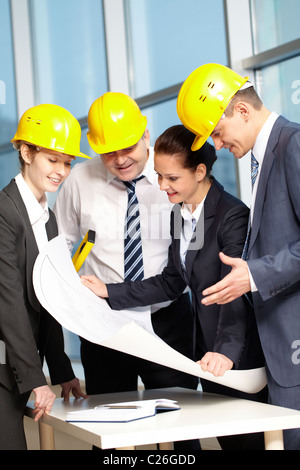 Vier Ingenieure am Tisch stehen und diskutieren ein Projekt Stockfoto