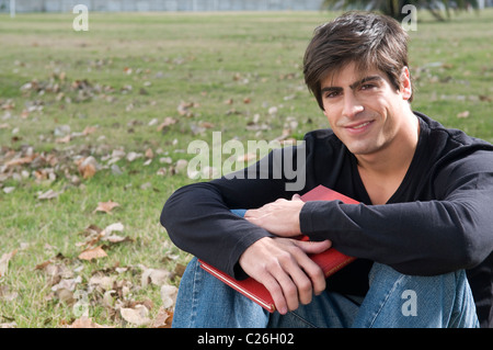 Student, Mensch, Blick, auf der Kamera sitzen, gelegen, auf einem, Feld, Campus, rot, Buch, lernen, lesen. Stockfoto