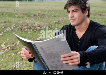 Mann, Student, gelegen, nach unten, auf ein Feld, Campus, Lesung, Lehrbuch, Magazin, Übung, Buch, lernen, üben, konzentriert. Stockfoto