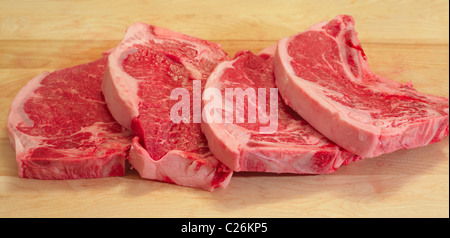 Vier Streifen Steaks auf ein Schneidebrett, bereit für den grill Stockfoto