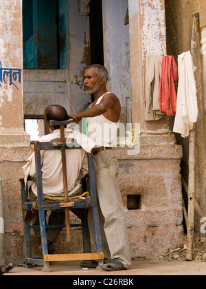 Barbier, schneiden Sie ein Mann Haare auf eines der Ghat in Varanasi, Indien Stockfoto