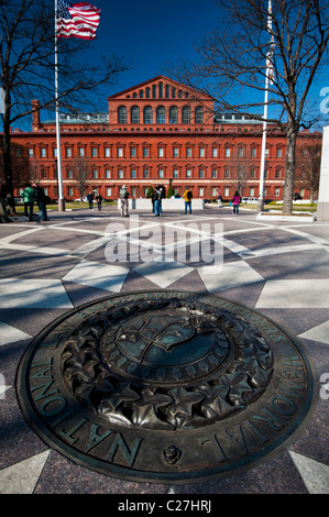 Plakette in der Mitte der nationalen Gesetz Durchsetzung Offiziere Gedenkstätte mit der National Building Museum im Hintergrund Stockfoto