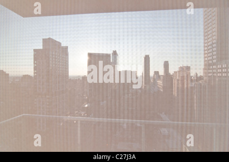 Ein Blick durch ein Blind von der Midtown-Wohnung in Manhattan, New York City. Das Empire State Building steht hoch auf der rechten Seite. Stockfoto