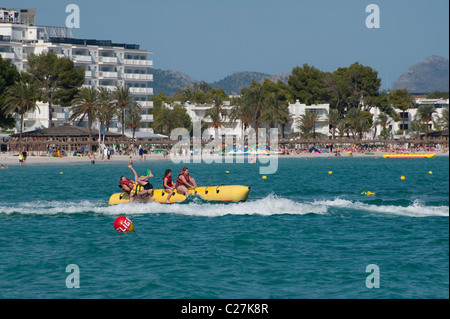 Urlauber genießen eine Fahrt auf einem Bananenboot in dem beliebten Küstenort Puerto de Alcudia, Spanien. Stockfoto