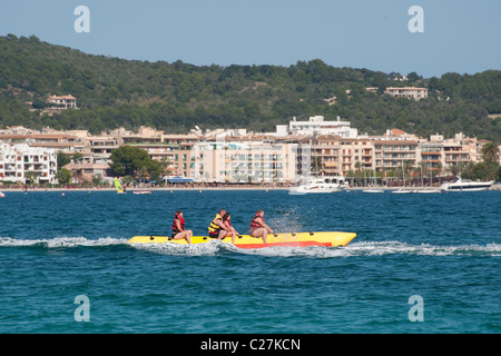 Urlauber genießen eine Fahrt auf einem Bananenboot in dem beliebten Küstenort Puerto de Alcudia, Spanien. Stockfoto